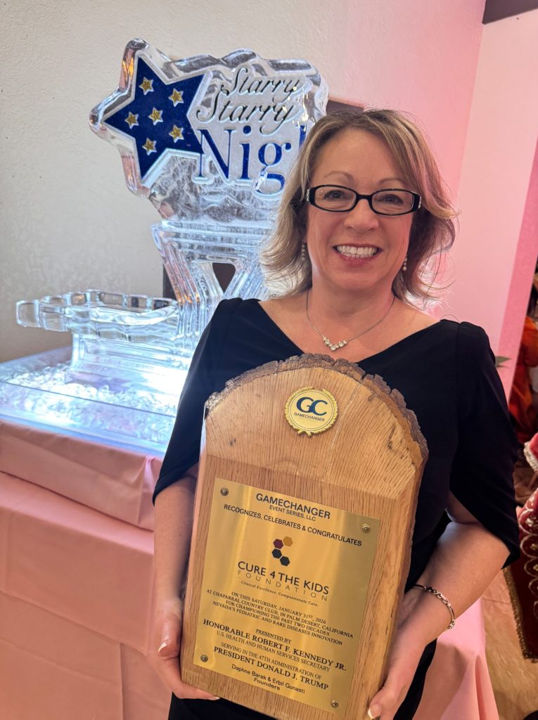 Annette Logan-Parker holding the Gamechanger Award at the 2026 Starry Starry Night Gala recognizing Cure 4 The Kids Foundation for pediatric and rare disease innovation.